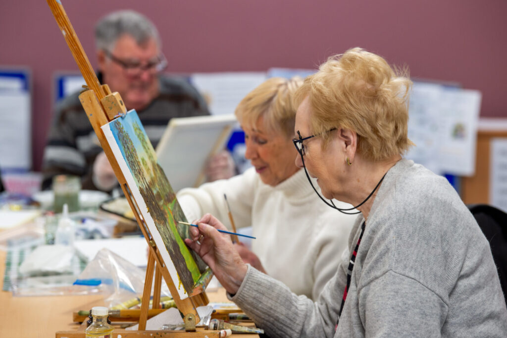 Two members discussing the art work on the easel